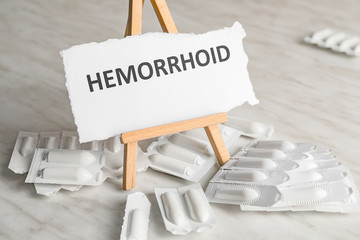 Hemorrhoidal suppositories and paper with word HEMORRHOID on light background
