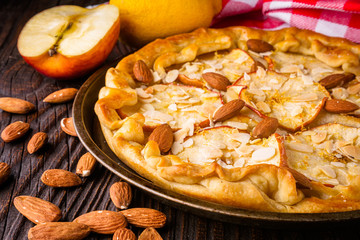 crispy apple galette with almonds on rustic wooden background
