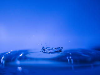 Water drop creating waves ripples and air borne water droplet