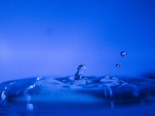 Water drop creating waves ripples and air borne water droplet