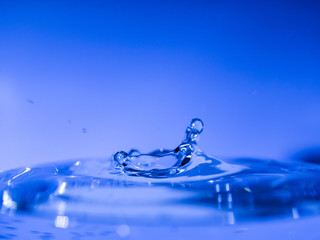 Water drop creating waves ripples and air borne water droplet