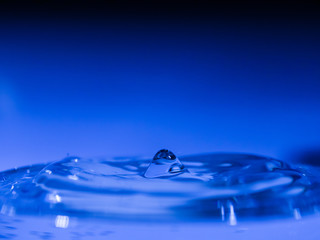 Naklejka na ściany i meble Water drop creating waves ripples and air borne water droplet