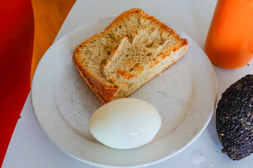 Toast, hard boiled egg and avocado on a plate with carrot juice.