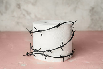 Toilet paper with barbed wire on table. Hemorrhoids concept