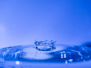 Water drop creating waves ripples and air borne water droplet