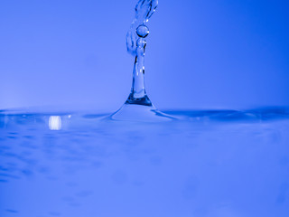 Water drop creating waves ripples and air borne water droplet