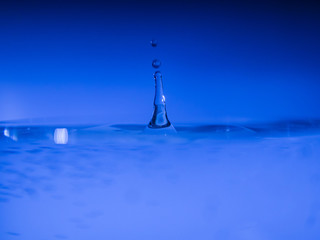 Water drop creating waves ripples and air borne water droplet