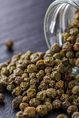 green peppercorns on dark slate stone background