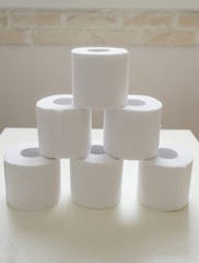 Stack of toilet paper rolls on wooden table. Closeup