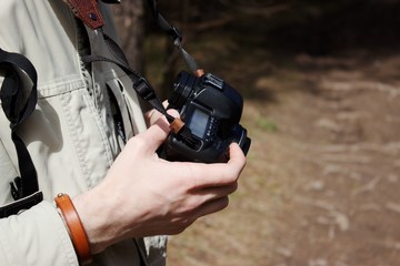 man holds a camera in his hands in the forest in the sunlight
