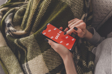 Sale on the phone screen. Woman holds a phone in his hand and sees the inscription sale. Online...