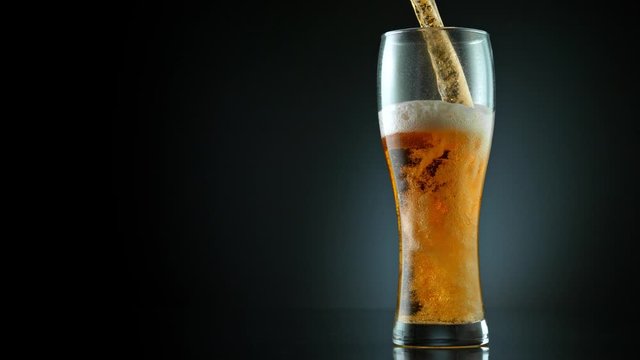Super Slow Motion Shot of Pouring Fresh Beer into Glass on Black Background at 1000fps.