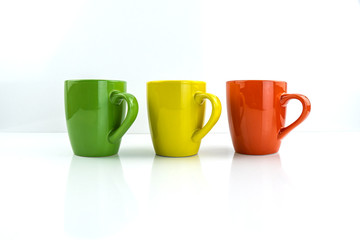 Porcelain cups of different colors stand on a white background.