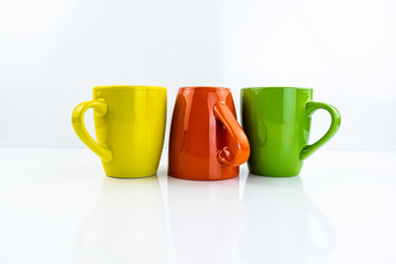Porcelain cups of different colors stand on a white background.