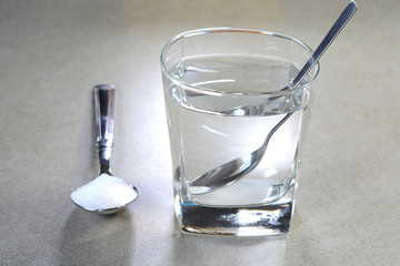 Salt water in a glass cup and salt in a teaspoon. Salt water has high level of minerals and salt...