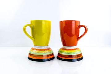 Porcelain cups of different colors stand on a white background.