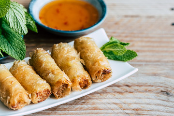 Nems au poulet accompagné de sauce piquante et feuilles de salade et menthe fraiche