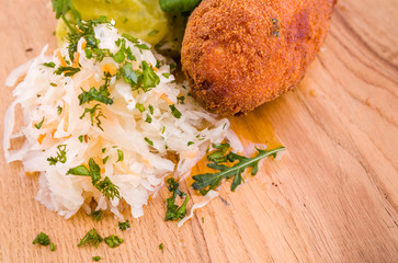 Fried cutlet, mashed potatoes, sauerkraut and pickled mushrooms on a wooden board