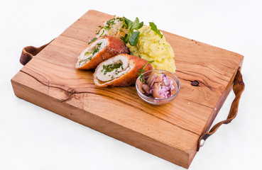 Fried cutlet cut in half, mashed potatoes, sauerkraut and pickled mushrooms on a wooden board