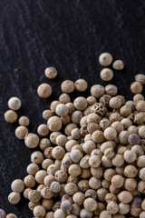 white peppercorns on dark slate stone background