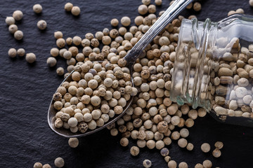 white peppercorns on dark slate stone background