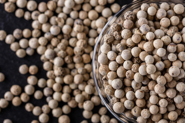 white peppercorns in glass bowl on stone background