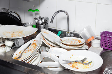 Metal sink full of dirty dishes, crockery, tableware