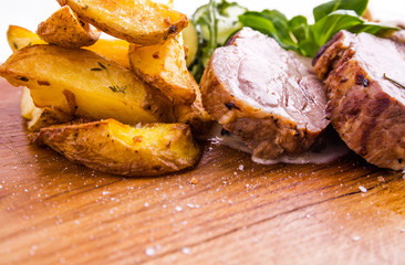 Fried pork neck with potato..gratin and creamy mushroom sauce on a wooden board