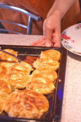 Woman taking delicious homemade pies from table, top view