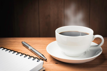 Wooden table desk with coffee. Workspace with note book, pen and coffee cup on wooden background with copy space.