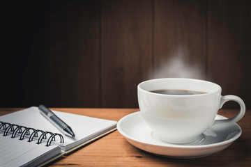 Wooden table desk with coffee. Workspace with note book, pen and coffee cup on wooden background with copy space.