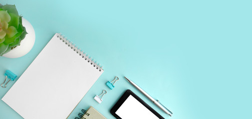 Minimalist workplace  with empty notepad, smartphone, succulent and stationery on mint background.  Online education or business concept.  Banner / header with copy space