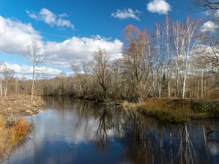 river view from the bridge, small river in early spring, blue sky and reflections in the water
