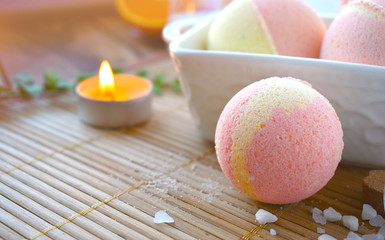 Still life spa resort treatment with bath bombs and candle on wooden background. Natural aromatherapy and relax concept. Sun light effect.