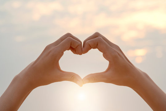 Female hands in the form of heart against sunlight in sunset sky, Love concept, Hands in shape of love heart, love Concept, Heart-shape hand gesture