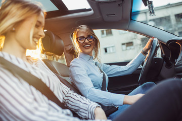 Two female friends enjoying road trip traveling at vacation in the car