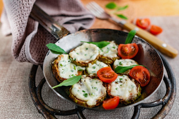 Pan-fried zucchini with garlic sauce and cherry tomatoes. Next to arugula, napkins, fork and mayonnaise. A colorful appetizer dish in a rustic setting
