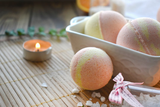 Spa resort setting. Still life image with bath bombs and candle on wooden background. Spring or summer relax concept.