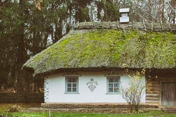 Classic ancient Ukrainian house with haulm roof, decorated by paintings and abandoned by residents in 21 century. Old clay house with paintings