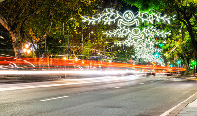 a night image of one of the busy nights leading up to christmas with cars rushing past and christmas lights in the background