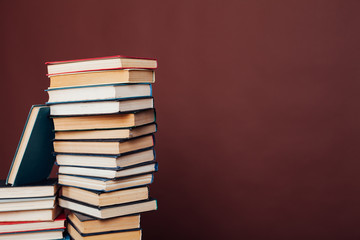 many stacks of educational books for college exams in the library on a brown background