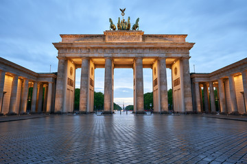 berlin germany, deserted brandenburg gate with reflections on the wet asphalt and with clouds at the sunset. special perspective as close-up from the ground, 