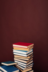 many stacks of educational books for college exams in the library on a brown background