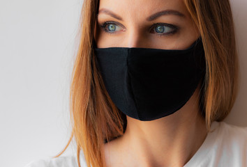 Close-up portrait of a young woman in a black medical mask and white T-shirt on white background. Quarantine, coronavirus epidemic pandemic, covid-19. Stay home concept. Virus protection. .