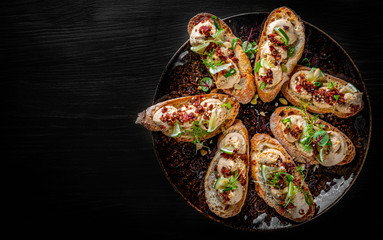 Fresh bruschettas pate in plate on black wooden table background