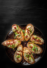 Fresh bruschettas pate in plate on black wooden table background