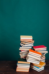 many stacks of educational books for exams at the university in the library on a green background