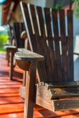 Vertical image, empty adirondack arm chairs in row on wood deck , focus on the arm , shallow depth...