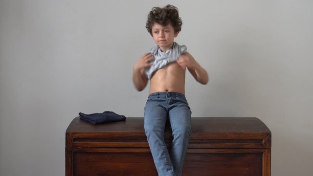 Europe, Italy , Milan -  children boy  five years with mask at home during quarantine at home due covid19 Coronavirus outbreak, life style in apartment - learn to wear alone the t-shirt and sweater