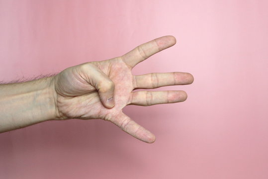 Male hand with fair skin shows a gesture, hand on a light pink background. Open hand with thumb held, number four. Stock photo for web and print.  - Powered by Adobe